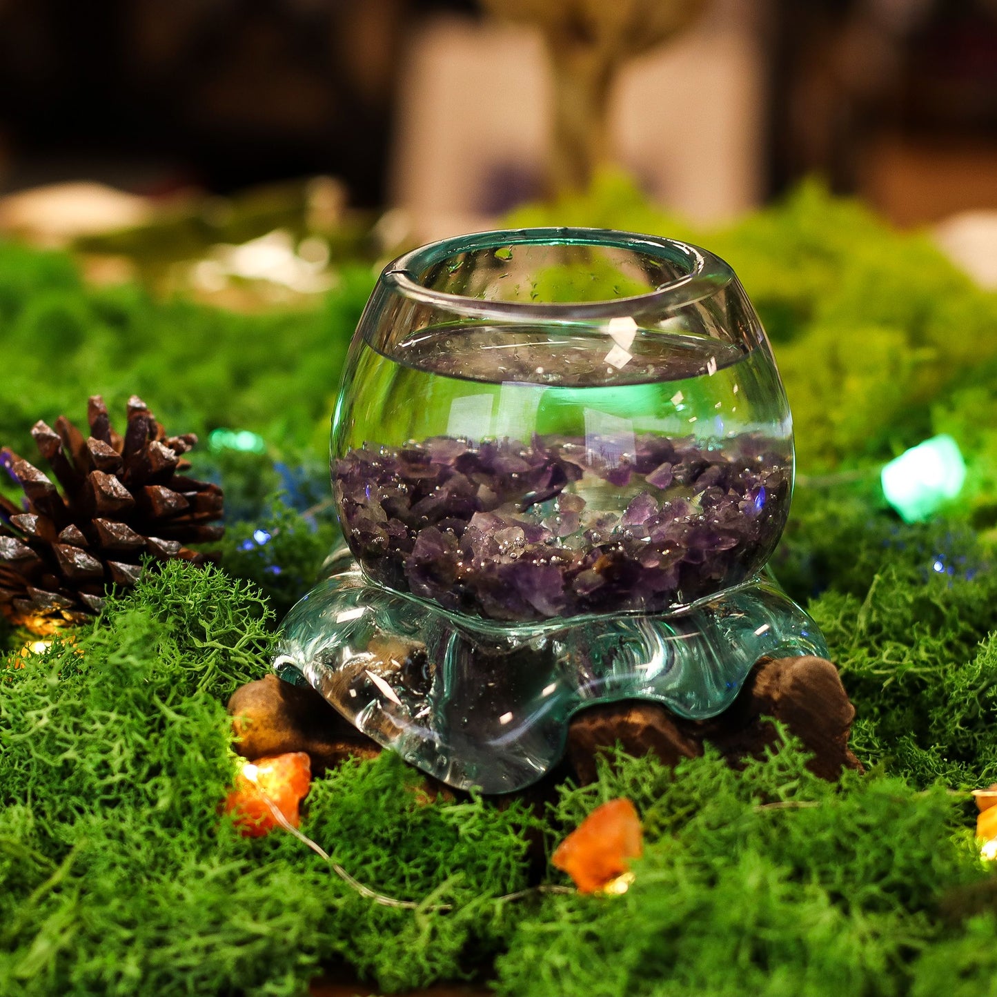 Glass container with purple crystals on a grassy surface with decorative elements