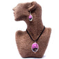 Necklace with a pink pendant on a brown textured stand against a white background