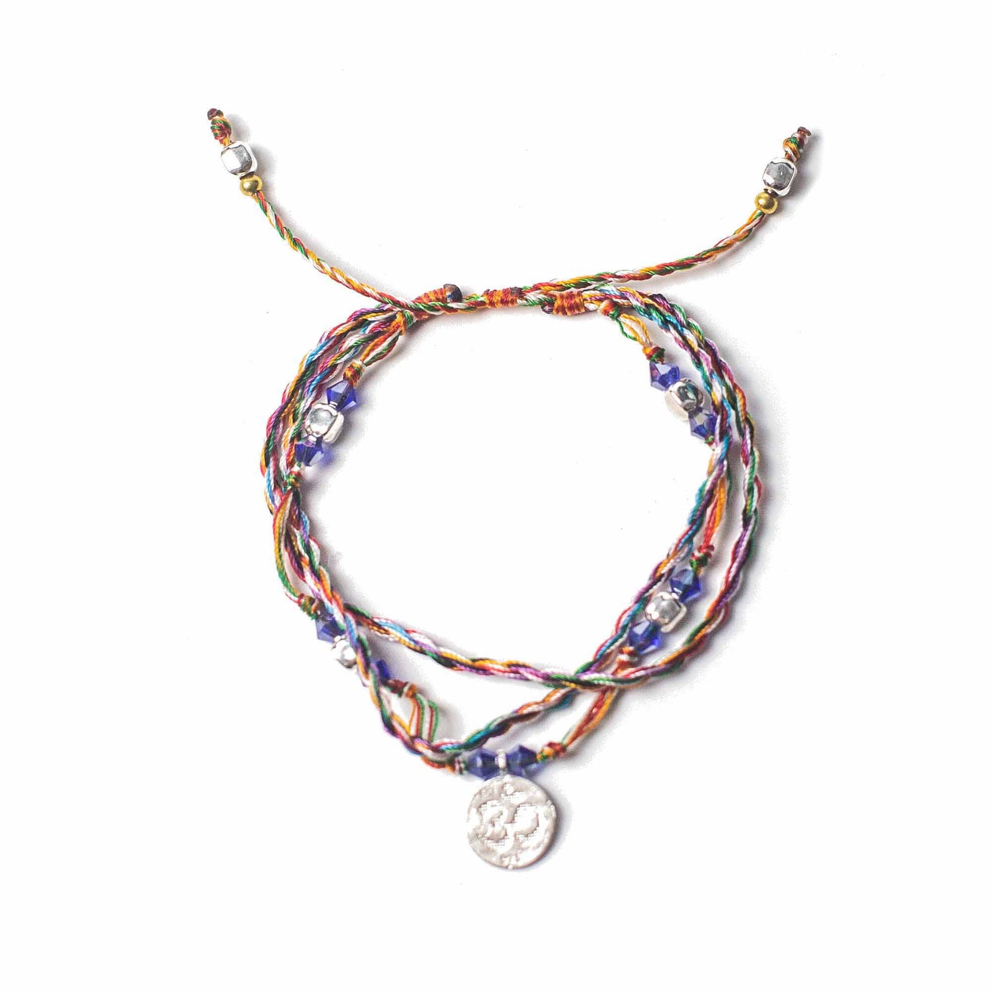 Multicolored braided bracelet with a silver charm on a white background