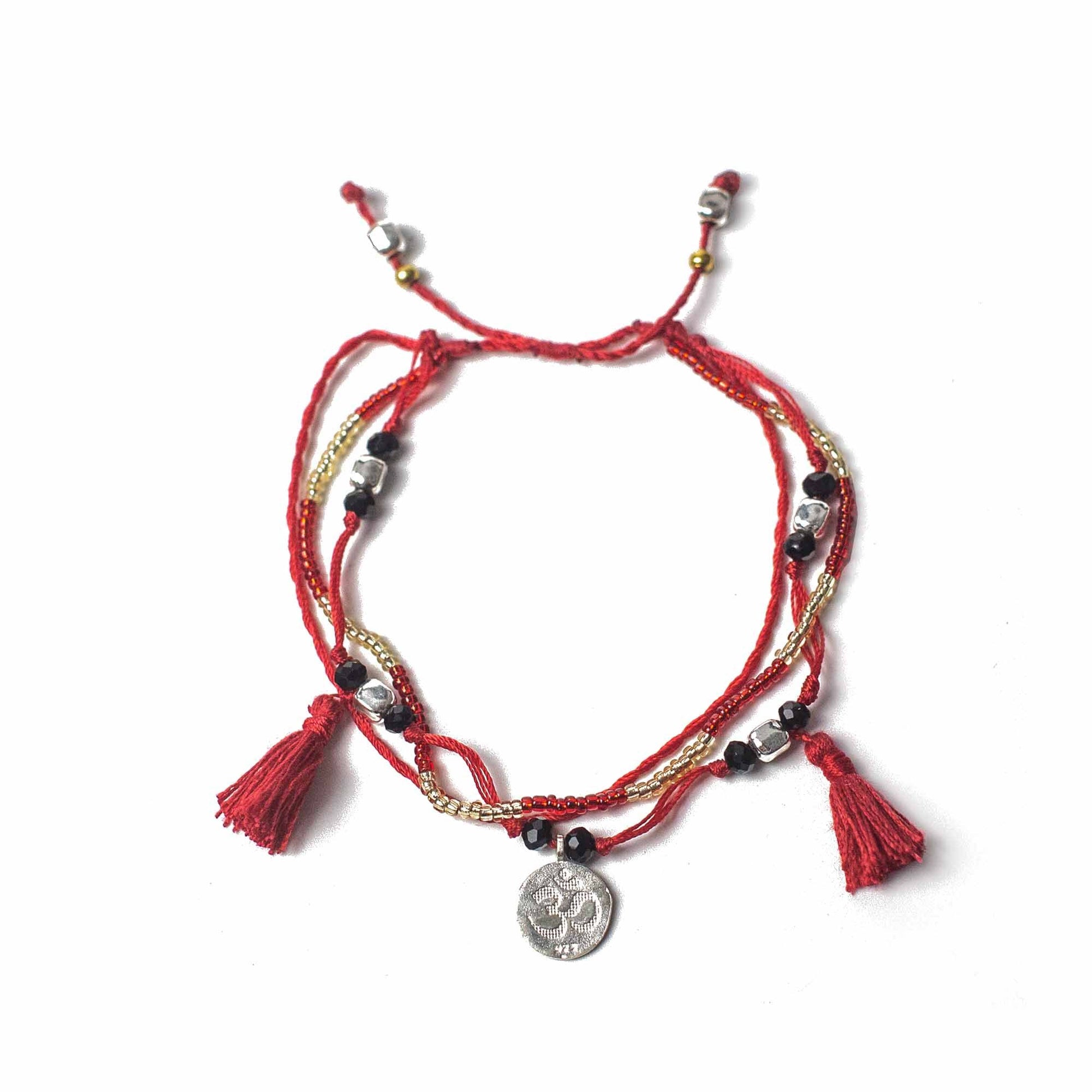 Red bracelet with tassels and a coin charm on a white background