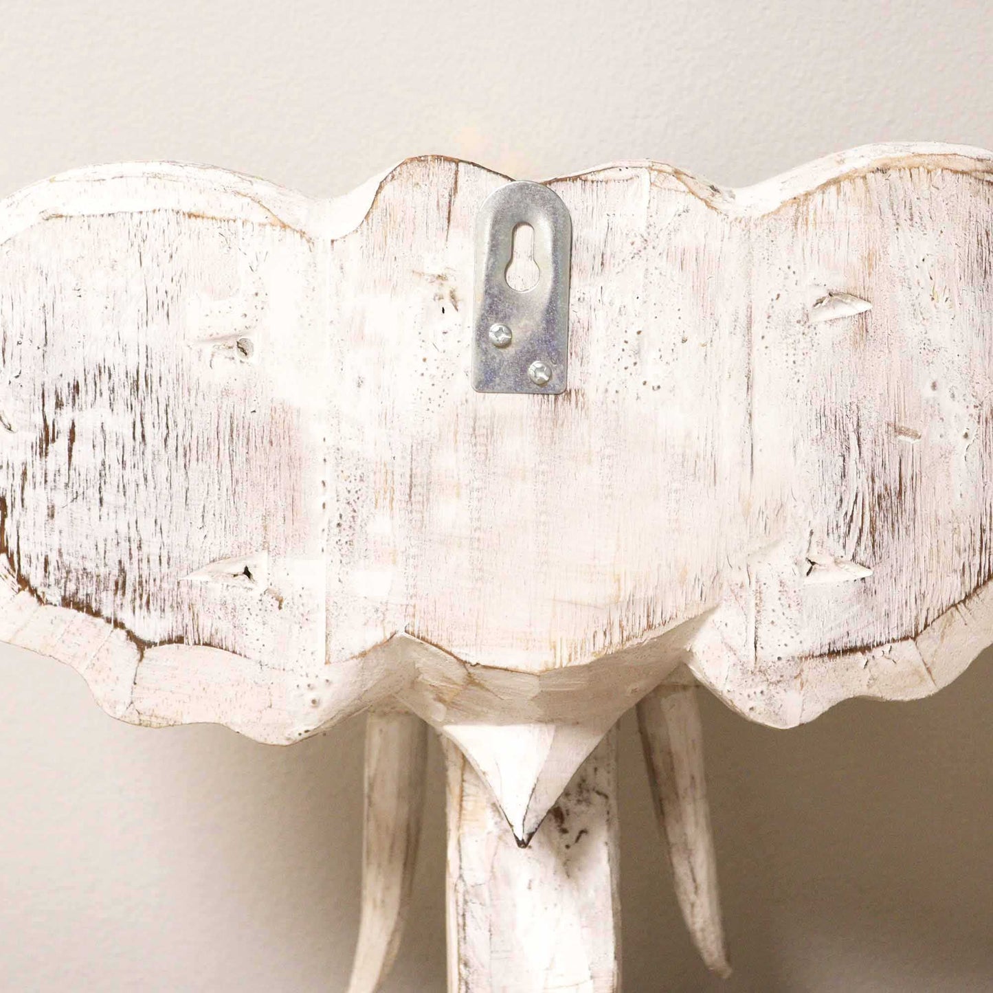 White distressed elephant head wall decoration on a plain background