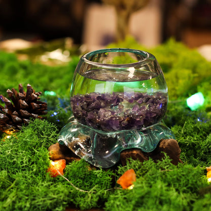 Glass container with purple crystals on a grassy surface with decorative elements