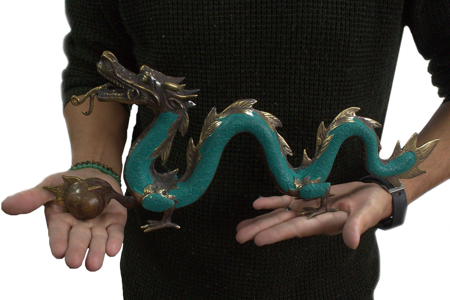 Person holding a large decorative dragon sculpture with hands, wearing a black sweater.