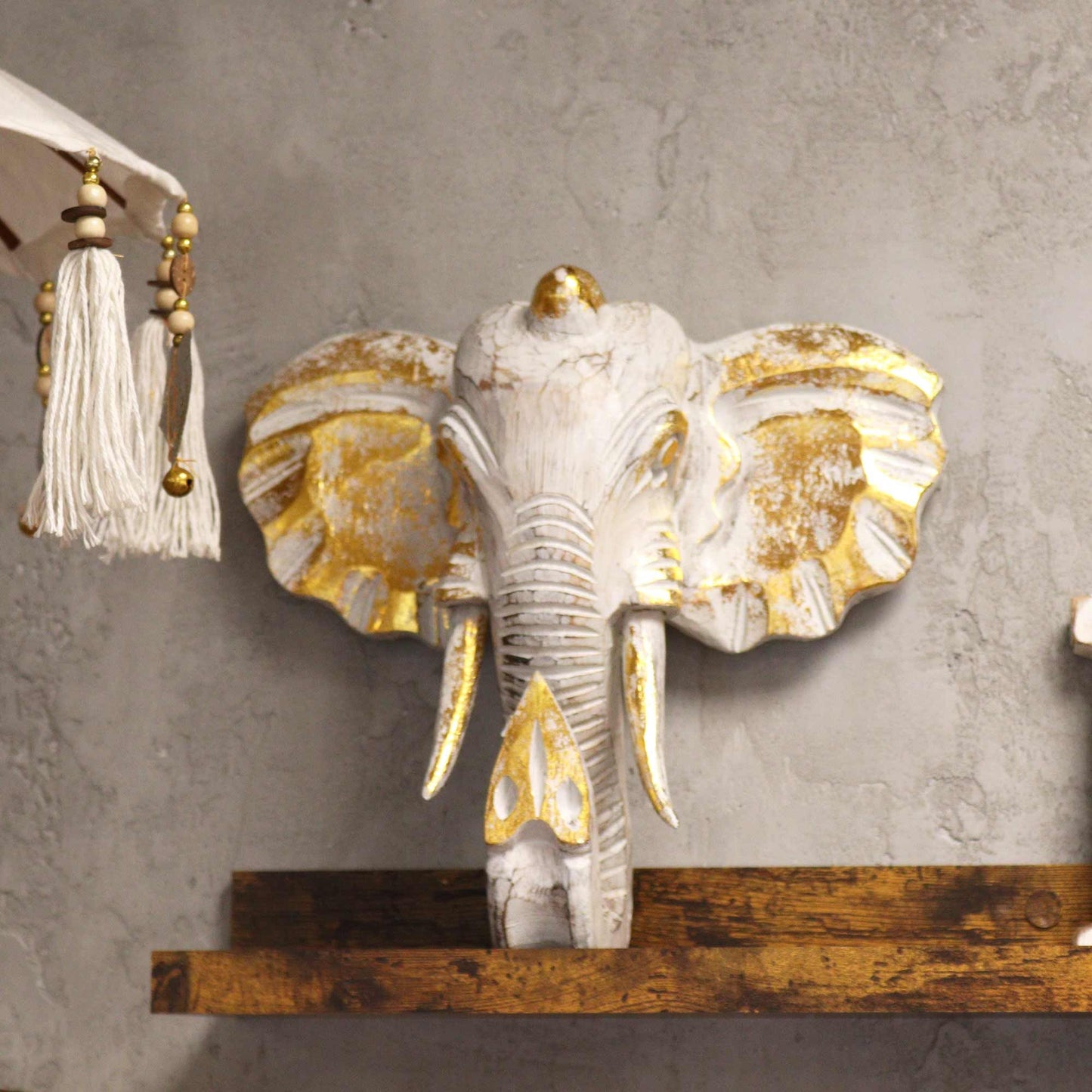 Decorative elephant head with gold accents on a gray wall.
