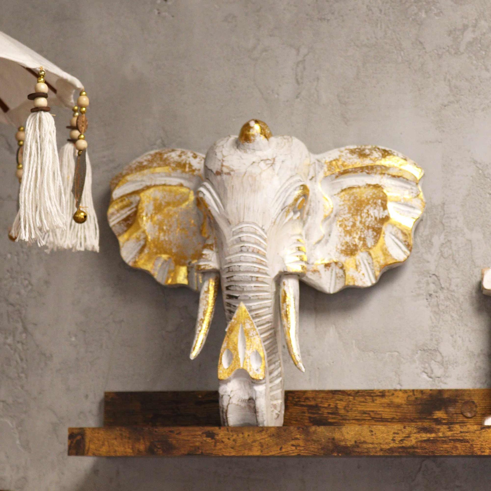 Decorative elephant head with gold accents on a gray wall.