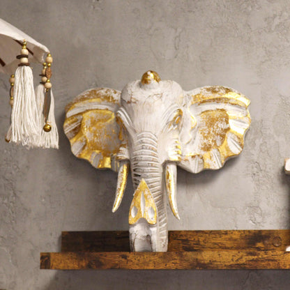 Decorative elephant head with gold accents on a gray wall.